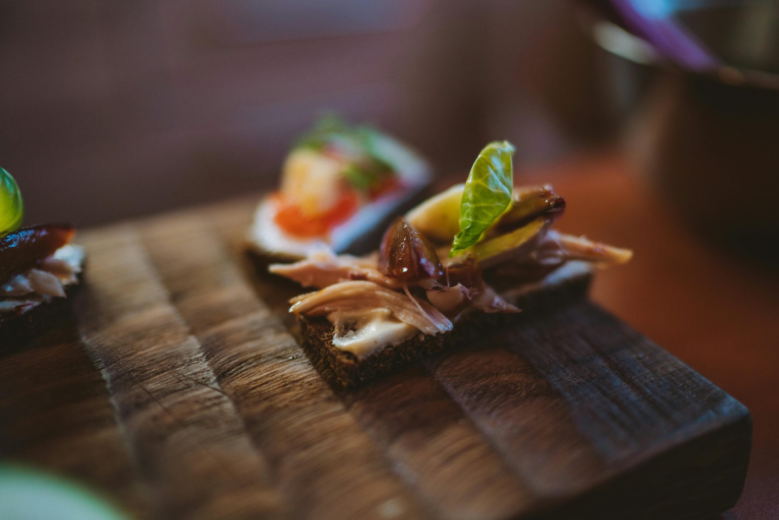 Delicious gourmet canapé with meat and greens on rustic wooden board.