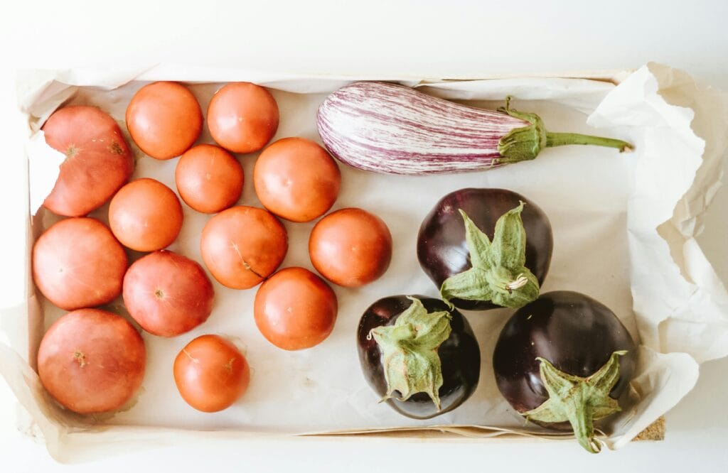 Vibrant tomatoes and eggplants on parchment paper showcasing fresh, healthy vegetables.