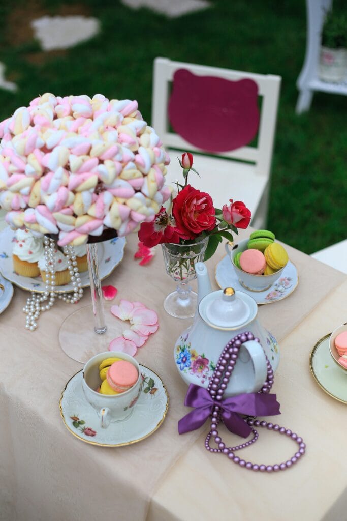 Charming outdoor tea setting with macarons, marshmallows, and vintage china. Perfect for celebrations.