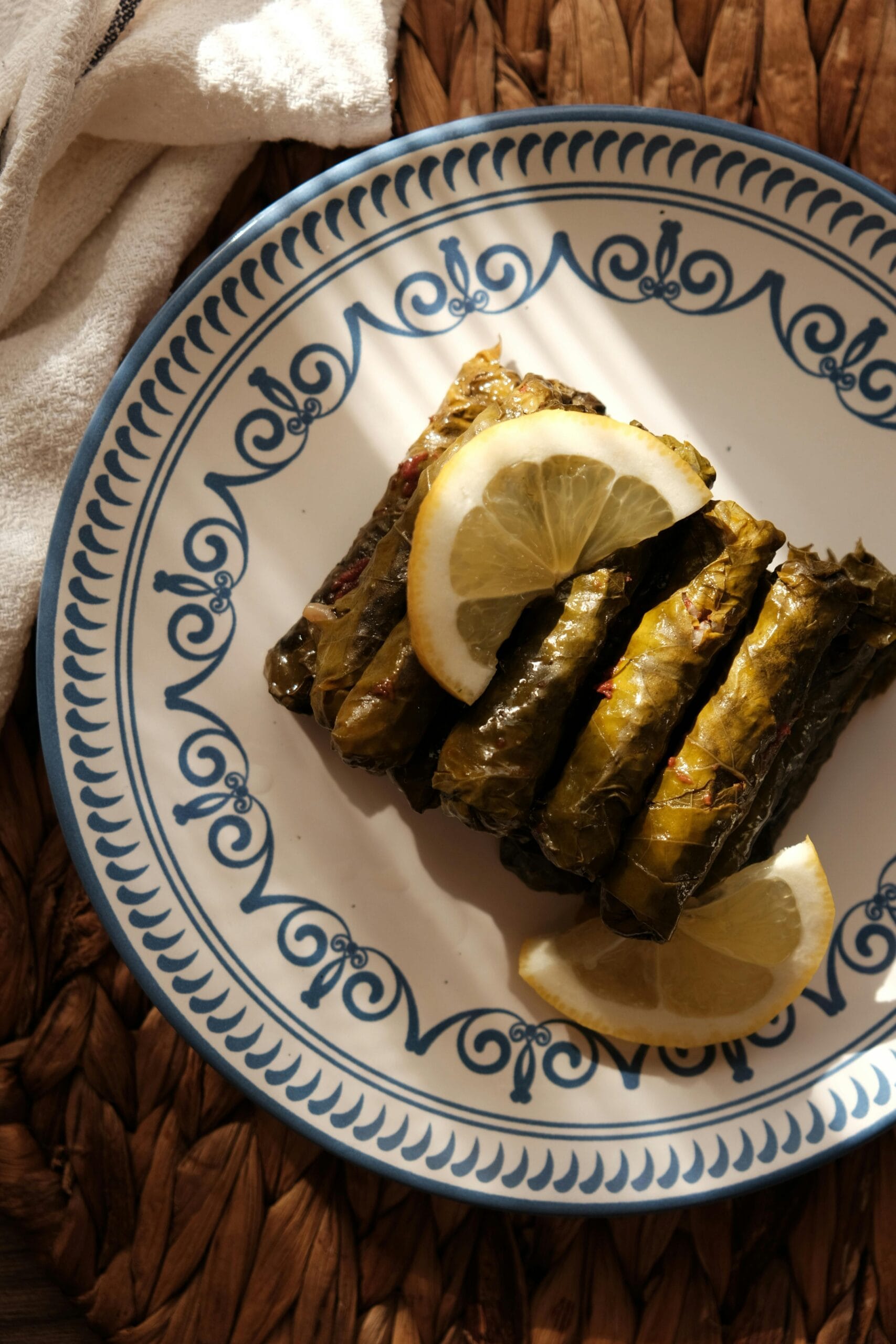 Savory stuffed grape leaves served on a decorative plate with lemon slices.